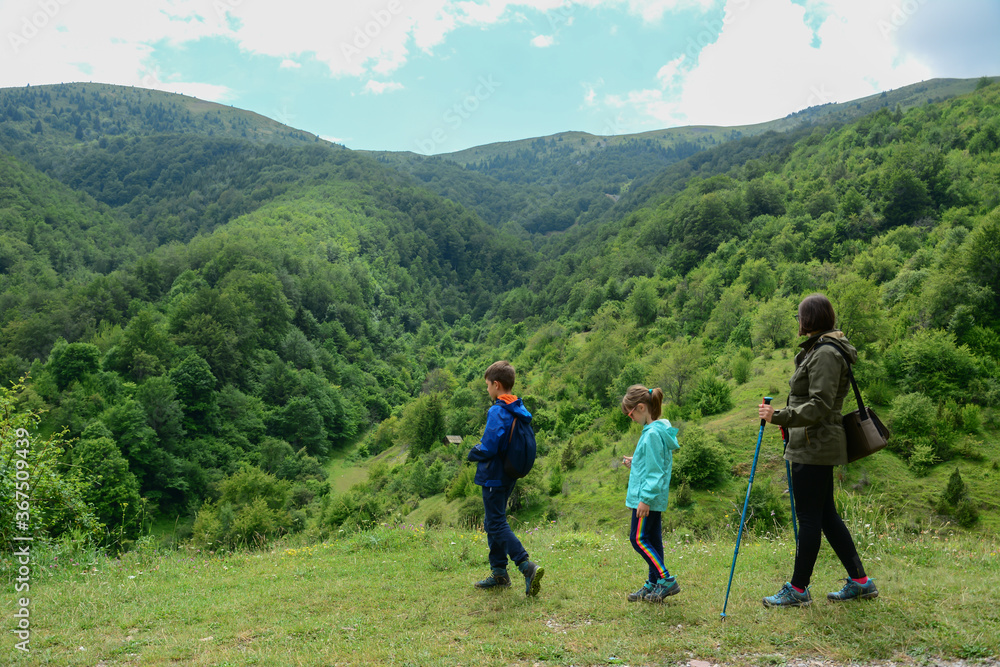Happy family are hiking in the mountains. Active family, mother and children mountaineering in the nature. Woman and two children hike on the mountain trail. Happy family are hiking in the mountains. Active family, mother and children mountaineering in the nature. Woman and two children hike on the mountain trail.