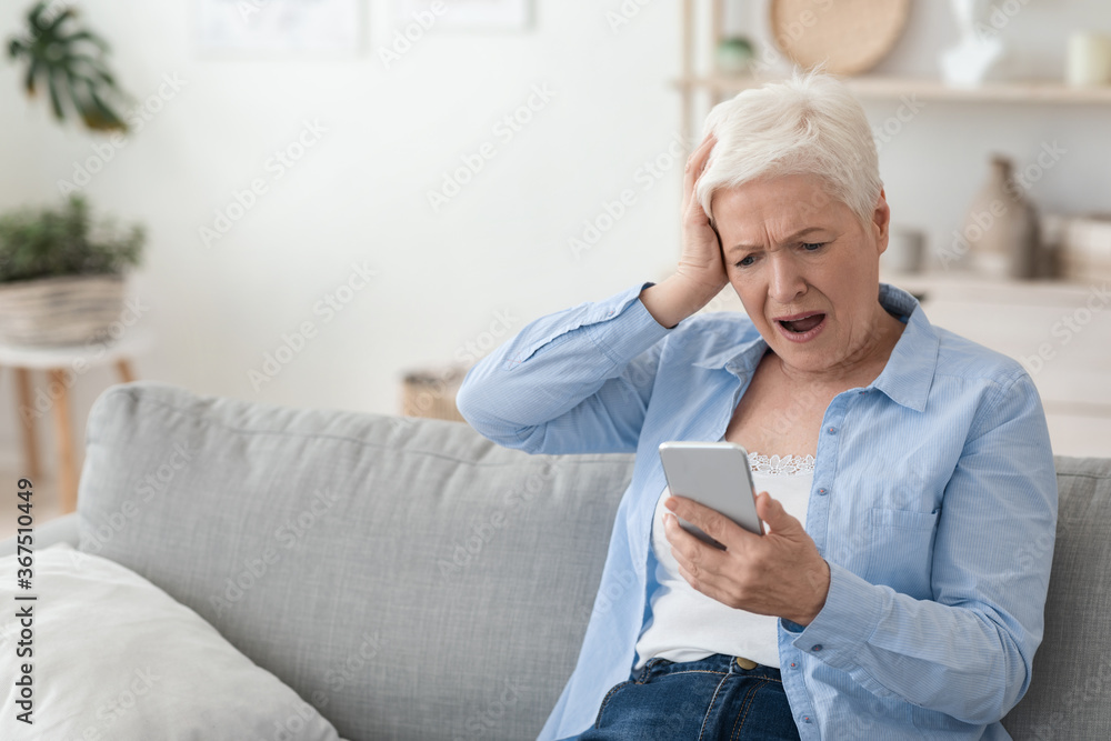 Mobile Scams Concept. Shocked Senior Woman Looking At Smartphone Screen In Frustration Mobile Scams Concept. Shocked Senior Woman Looking At Smartphone Screen In Frustration