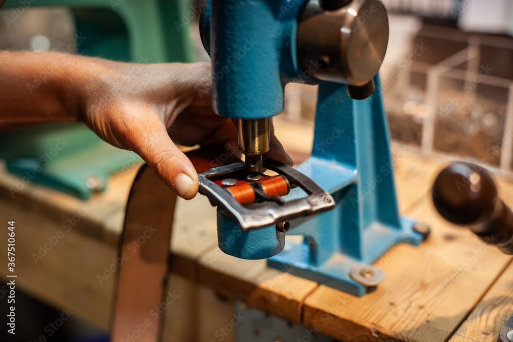 Hands of female leather artisan creating a hand-made belt Hands of female leather artisan creating a hand-made belt