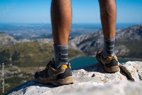 Close up of the legs of a man standing on a rock while trekking on a mountain looking at the stunning views of Serra de Tramuntana (Mallorca, Spain) © Daniel