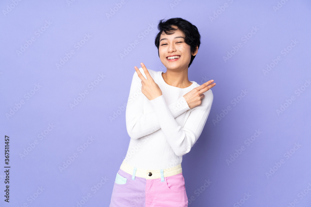 Young Vietnamese woman with short hair over isolated purple background smiling and showing victory sign Young Vietnamese woman with short hair over isolated purple background smiling and showing victory sign