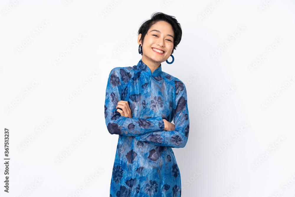 Young Vietnamese woman with short hair wearing a traditional dress over isolated white background keeping the arms crossed in frontal position Young Vietnamese woman with short hair wearing a traditional dress over isolated white background keeping the arms crossed in frontal position