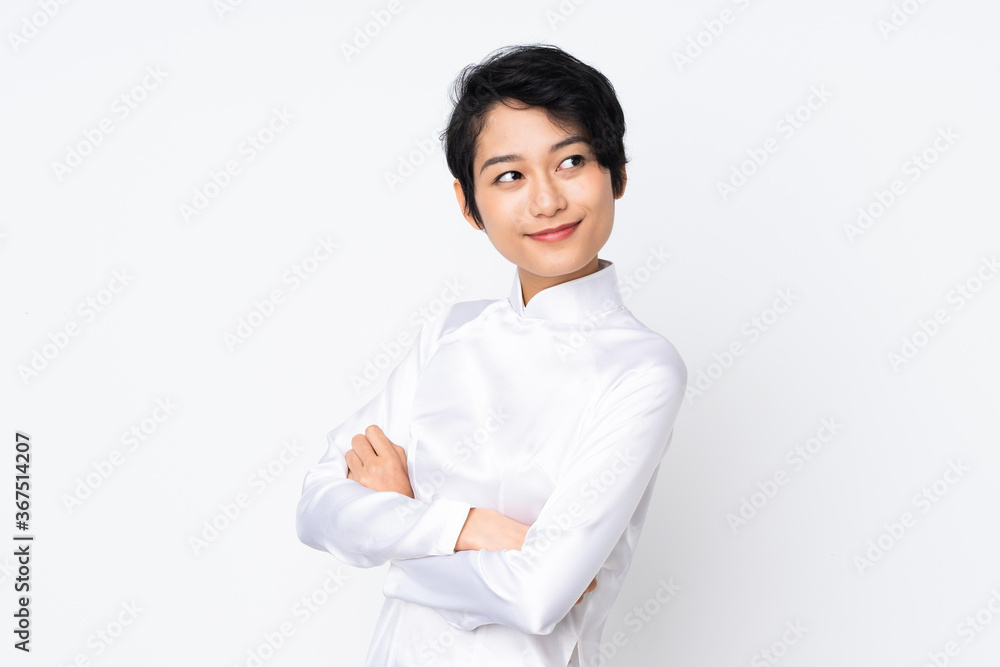 Young Vietnamese woman with short hair wearing a traditional dress over isolated white background with arms crossed and looking forward Young Vietnamese woman with short hair wearing a traditional dress over isolated white background with arms crossed and looking forward