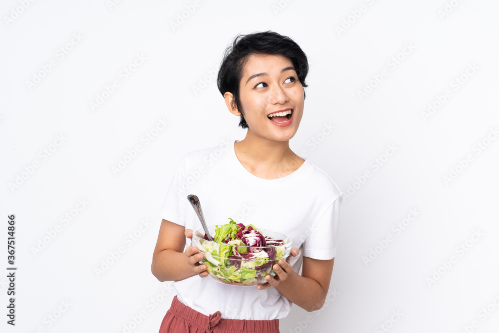 Young Vietnamese woman with short hair holding a salad over isolated background Young Vietnamese woman with short hair holding a salad over isolated background