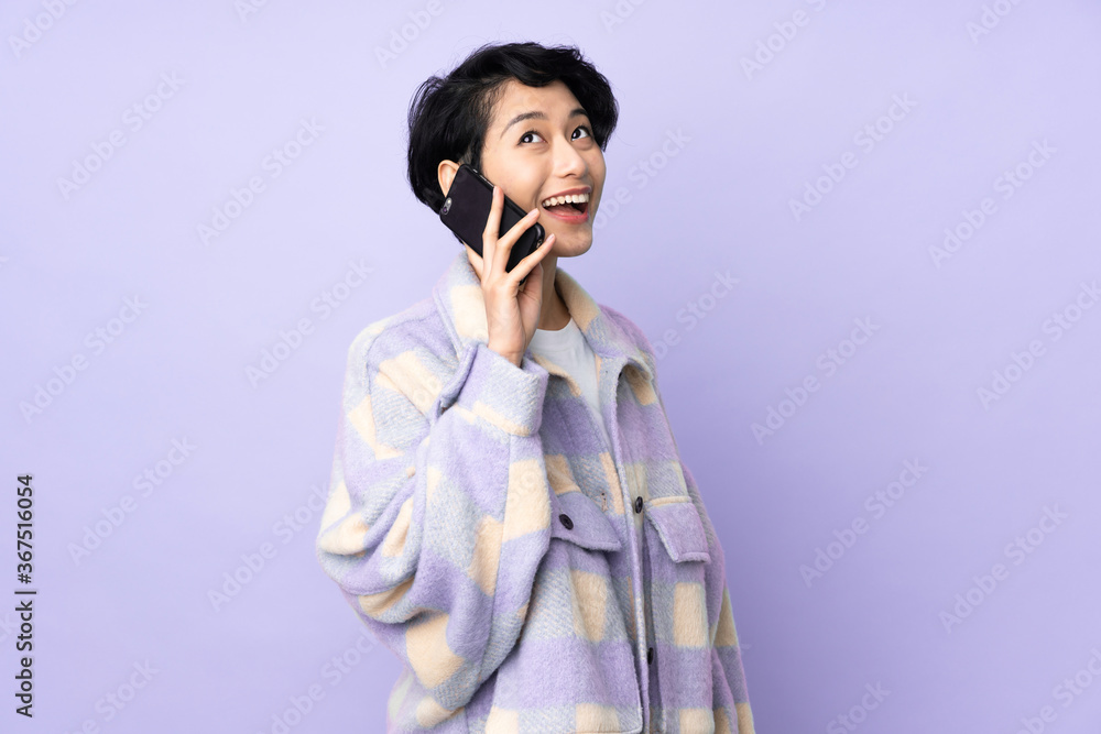 Young Vietnamese woman with short hair over isolated background keeping a conversation with the mobile phone Young Vietnamese woman with short hair over isolated background keeping a conversation with the mobile phone
