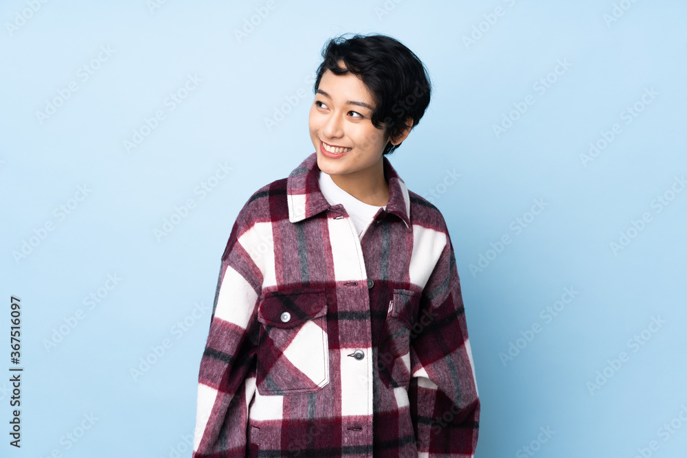Young Vietnamese woman with short hair over isolated background looking to the side and smiling Young Vietnamese woman with short hair over isolated background looking to the side and smiling