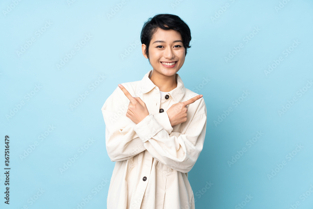 Young Vietnamese woman with short hair over isolated background pointing to the laterals having doubts Young Vietnamese woman with short hair over isolated background pointing to the laterals having doubts