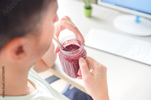 man working on the computer and drinking smoothie in home office