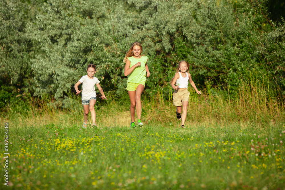 Kids, children running on meadow in summer's sunlight. Look happy, cheerful with sincere bright emotions. Cute caucasian boys and girls. Concept of childhood, happiness, movement, family and summer. Kids, children running on meadow in summer's sunlight. Look happy, cheerful with sincere bright emotions. Cute caucasian boys and girls. Concept of childhood, happiness, movement, family and summer.