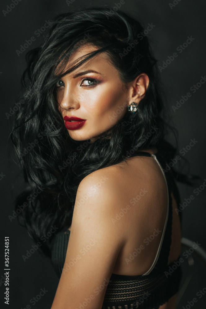Fashion model with wavy hairstyle. Attractive young girl with curly hair posing at studio. Face of a beautiful woman with long brown curly hair. Female face with evening makeup. Fashion model with wavy hairstyle. Attractive young girl with curly hair posing at studio. Face of a beautiful woman with long brown curly hair. Female face with evening makeup.