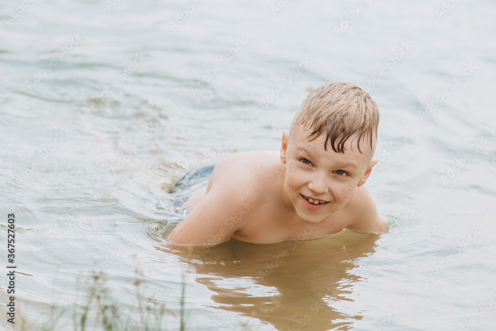 Happy boy swimmimg in the lake . Summer Holidays Happy boy swimmimg in the lake . Summer Holidays