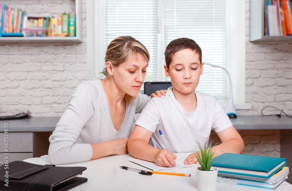 Mother helps son to do lessons. Home schooling and distance learning Mother helps son to do lessons. Home schooling and distance learning
