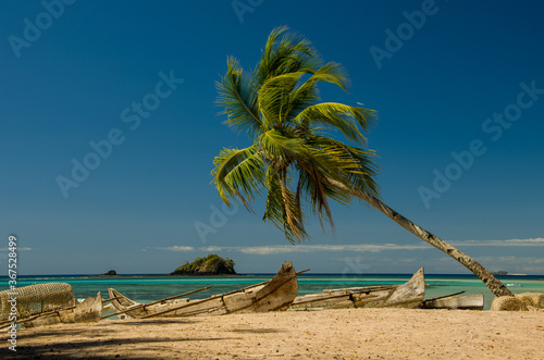 Pirogues et cocotier sur la plage de la baie d'Andilana, Nosy Be - Madagascar