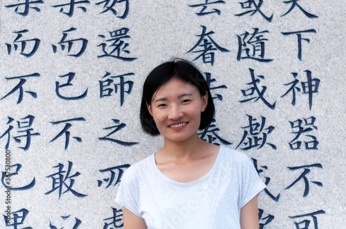chinese woman in front of laozhi taoism teachings.  chinese translation are random taoist teachings from lao zi.
