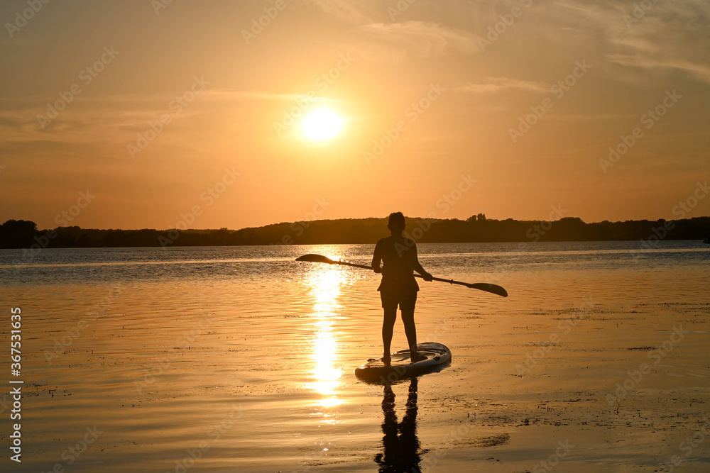 Silhouette of a boy on a paddle board at sunset