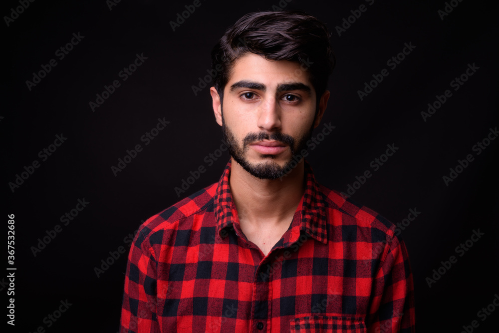 Fototapeta premium Young handsome bearded Persian man against black background