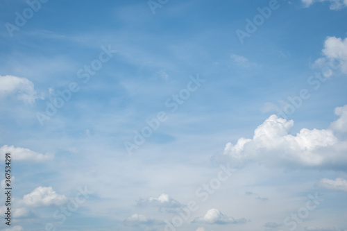 Fluffy white clouds float across the blue sky on a clear sunny summer or spring day. Empty space for inscriptions  form. Background sky. Blue and white wallpaper. Low angle view.