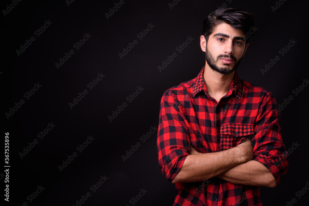 Young handsome bearded Persian man against black background Young handsome bearded Persian man against black background