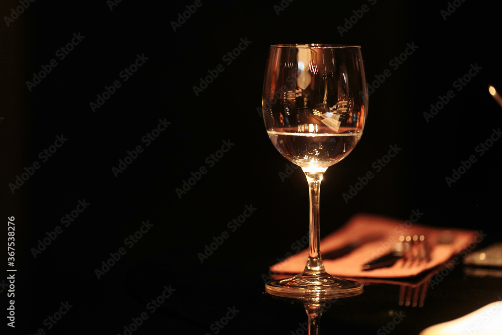 A glass of white wine on a glass table on a black background A glass of white wine on a glass table on a black background