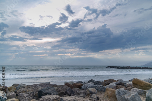 view of the pacific ocean, rocks on the beach, sky with clouds in california