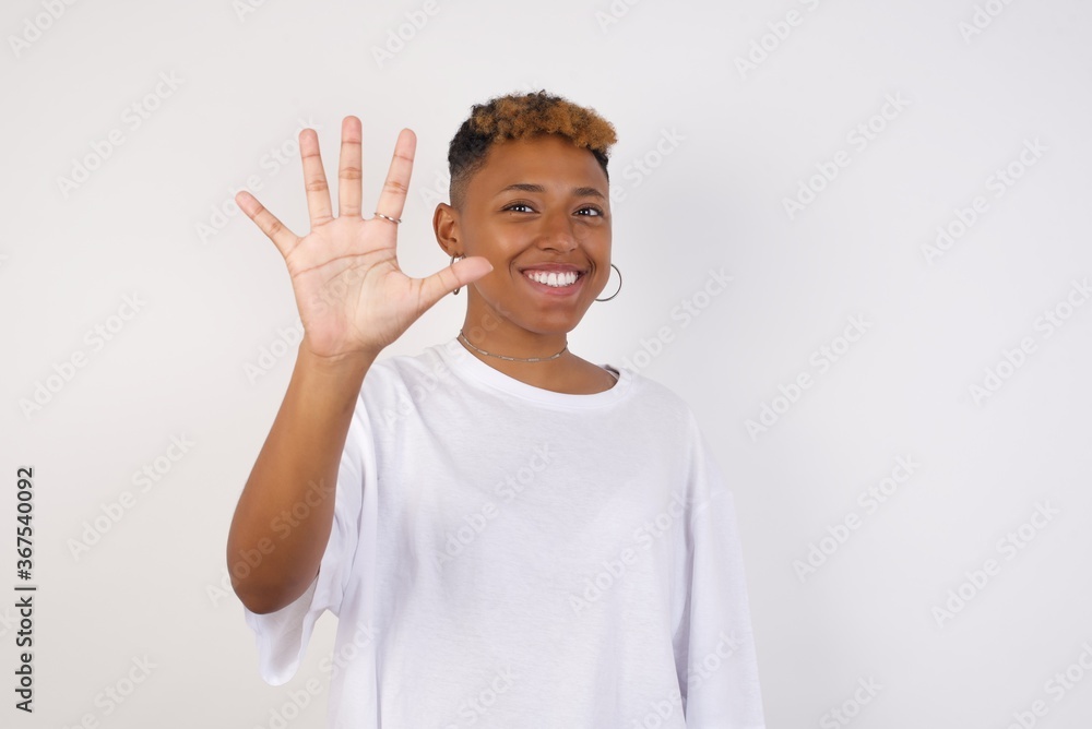 Young woman standing against gray wall showing and pointing up with fingers number five while smiling confident and happy. Young woman standing against gray wall showing and pointing up with fingers number five while smiling confident and happy.
