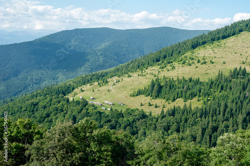 open mountain landscape with woodland and rural buildings © Petr
