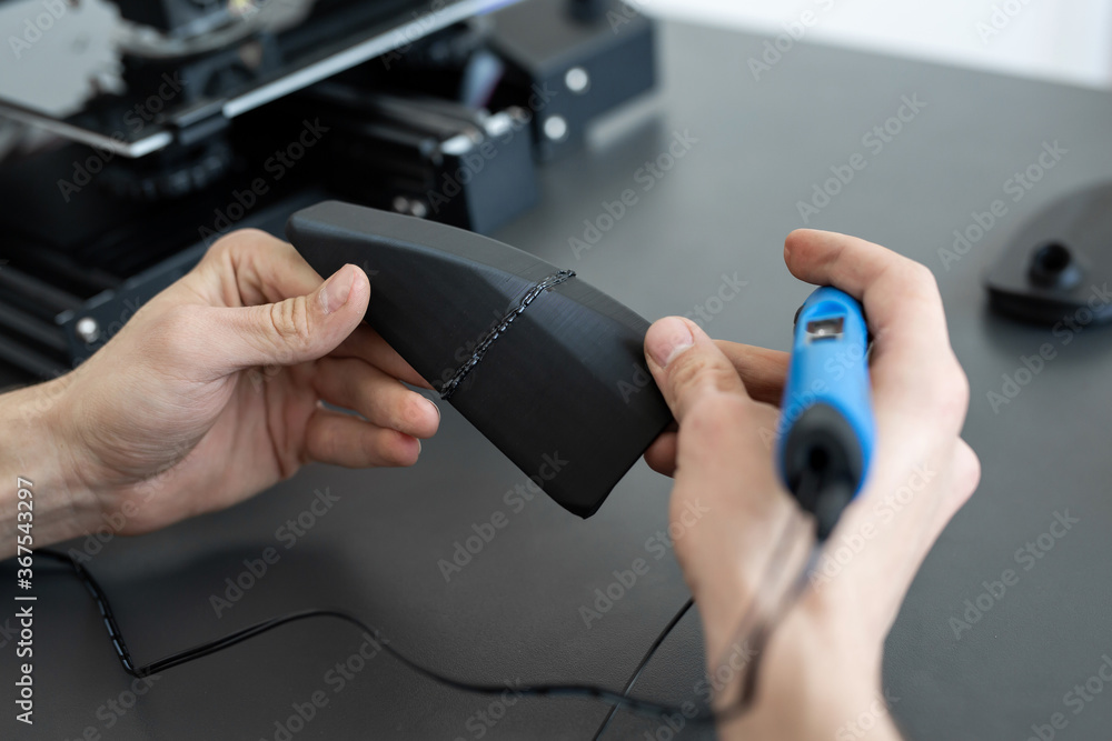 Man connects two 3D printer parts with a 3D pen Man connects two 3D printer parts with a 3D pen