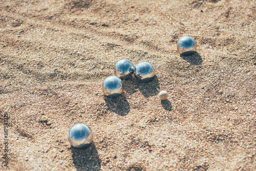 Playing boccia on the beach. Balls for playing boccia on the sand. Shiny chrome petanque balls with reflections.
