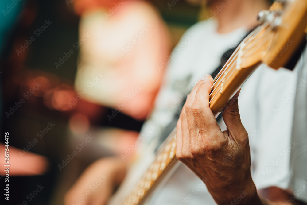 Close-up of a bass player's hand. Bass guitarist playing on the stage during the concert Close-up of a bass player's hand. Bass guitarist playing on the stage during the concert