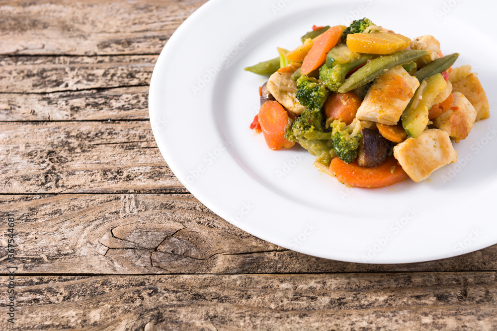 Stir fry chicken with vegetables on wooden table. Copy space Stir fry chicken with vegetables on wooden table. Copy space