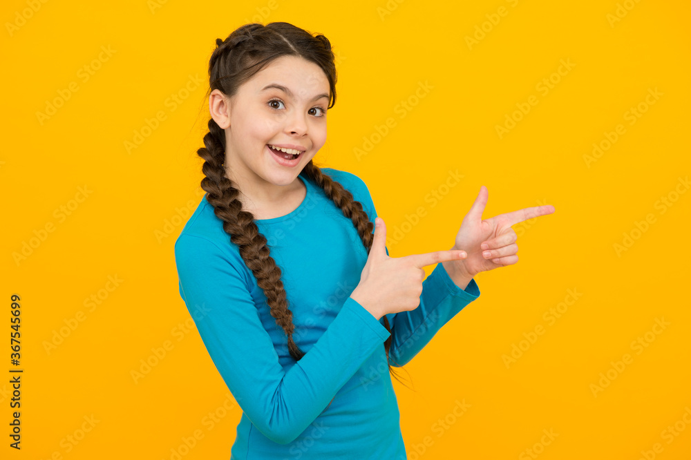 look at that. young beautiful smiling girl with fashionable hairstyle. kid on yellow background, copy space. Positive emotions. kid hairdresser salon here. Portrait of happy girl pointing finger look at that. young beautiful smiling girl with fashionable hairstyle. kid on yellow background, copy space. Positive emotions. kid hairdresser salon here. Portrait of happy girl pointing finger