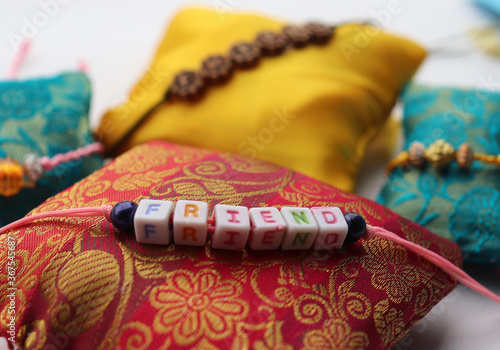 friend ship bands for friend ship day tied to pillow with friend word written beads on the thread of different colors yellow, red, blue