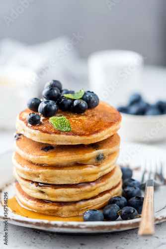 Blueberry pancakes stack poured with flower honey. Tasty breakfast pancakes with blueberries