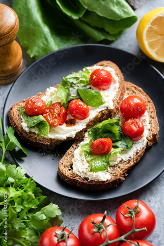 Bruschetta with ricotta and tomatoes on black plate. Gourmet italian open sandwich