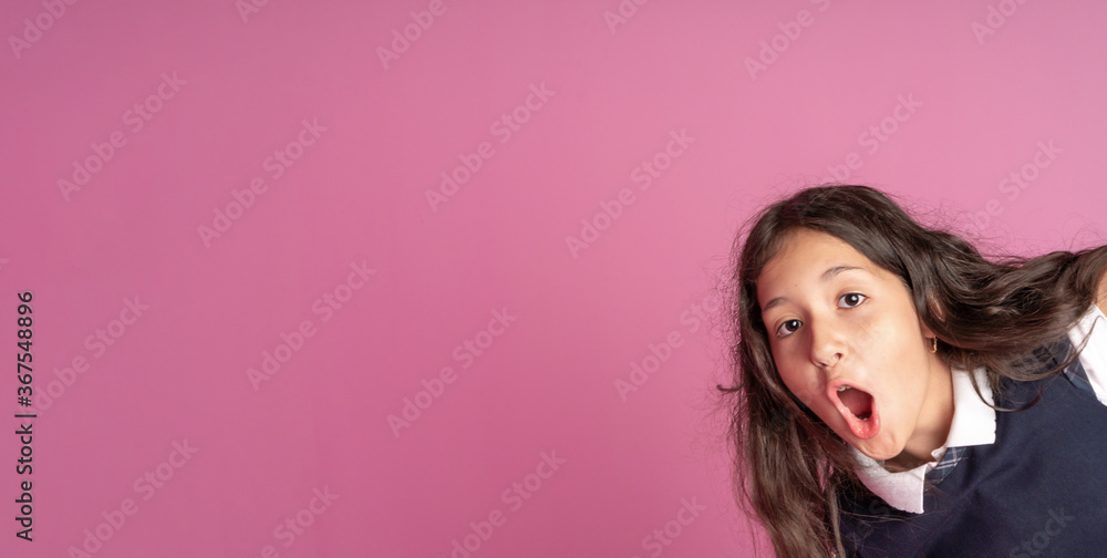 A charming girl with long curly dark hair in a school uniform with her mouth open with delight. Emotion of delight and surprise on your face. Studio photo. Back to school. A charming girl with long curly dark hair in a school uniform with her mouth open with delight. Emotion of delight and surprise on your face. Studio photo. Back to school.