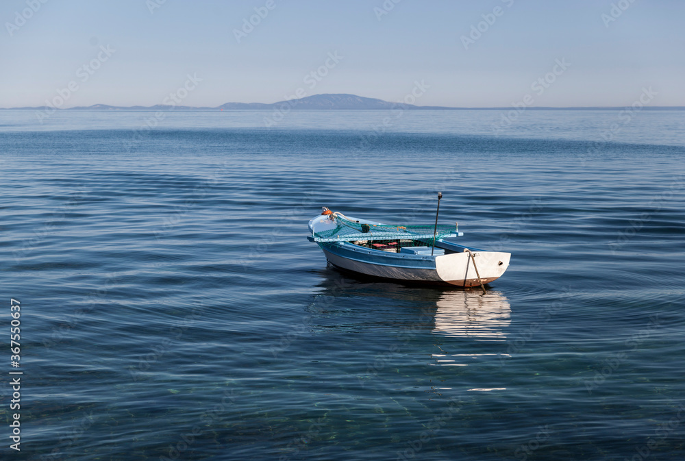 Small fishing boat on the blue sea and blue sky,peaceful and lonely,Novalja,Pag,Croatia Small fishing boat on the blue sea and blue sky,peaceful and lonely,Novalja,Pag,Croatia