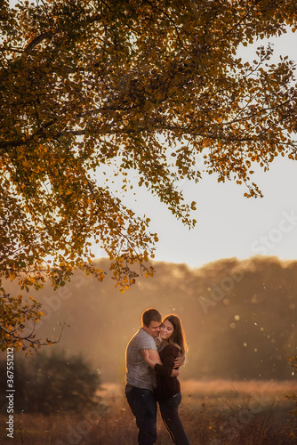 A young man and a girl are walking in the autumn forest. Happy lovers hold hands, hug each other, kiss, spend time together. Traveling during the cold season, on weekend days. Couple in love forever © farmuty