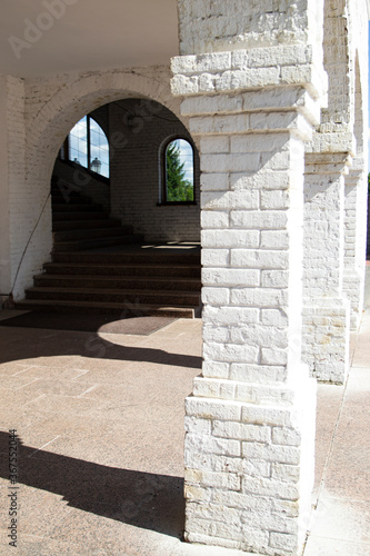 Arches in the white brick wall, shadows on the floor, a passage down the stairs