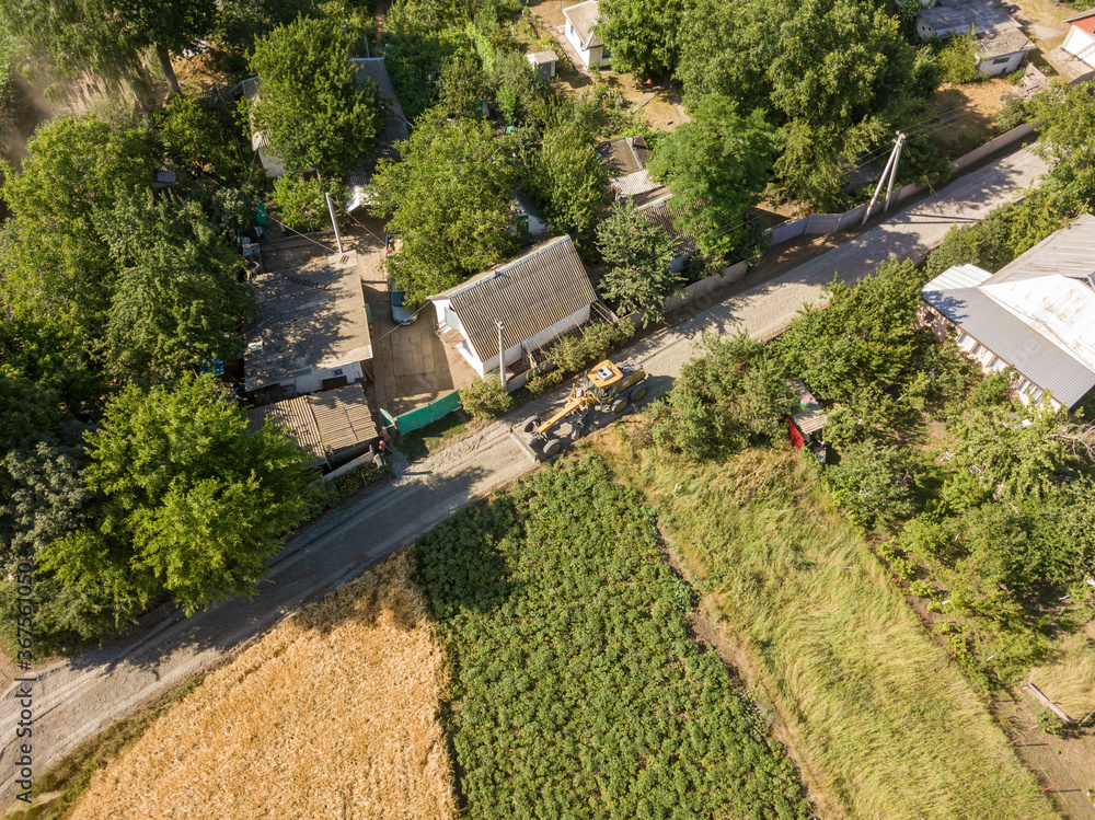Aerial drone view. A grader on a rural street in Ukraine. Aerial drone view. A grader on a rural street in Ukraine.