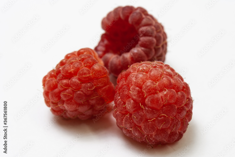Three ripe raspberries isolated on a white background close-up. Fresh raspberries without sheets on the table. Macro shooting. Healthy and wholesome food concept Three ripe raspberries isolated on a white background close-up. Fresh raspberries without sheets on the table. Macro shooting. Healthy and wholesome food concept