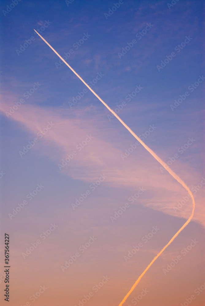 Vertical image of high altitude plane white trails in a colourful sky Vertical image of high altitude plane white trails in a colourful sky