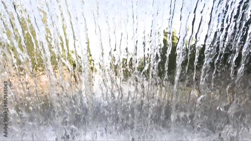 The texture of a transparent water wall from jets of water flows down. Close-up view The texture of a transparent water wall from jets of water flows down. Close-up view
