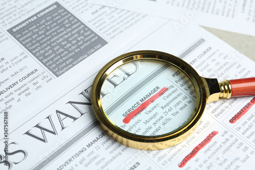 Magnifying glass on newspaper. Job search concept