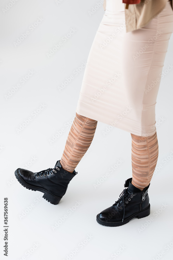 cropped view of girl in stylish striped tights and black boots on white cropped view of girl in stylish striped tights and black boots on white