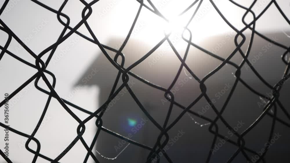 Sun and silhouette of buildings through wire mesh or mesh fence at sunset Sun and silhouette of buildings through wire mesh or mesh fence at sunset