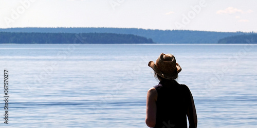 Woman with straw cowboy hat looking calm lake Päijänne near Pulkkilanharju ridge in Finnish Lakeland. photo