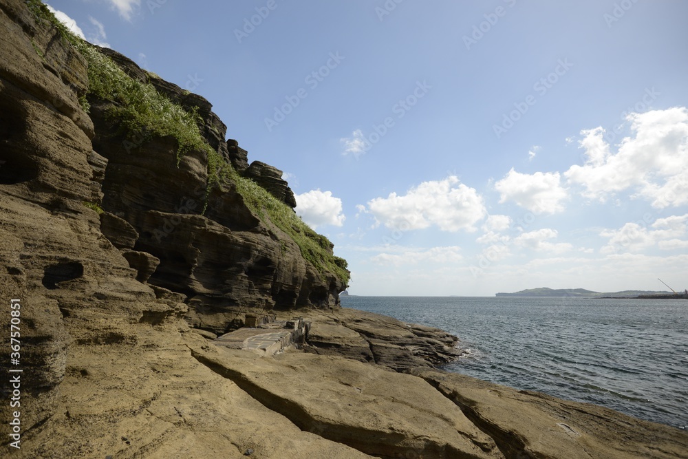Beautiful shot of rock formations near the water on a summer day in Jeju Island, South Korea Beautiful shot of rock formations near the water on a summer day in Jeju Island, South Korea
