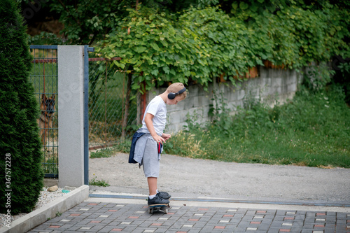 Caucasian Little boy riding a skateboard, wearing a headphones.
