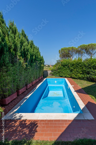 A swimming pool with blue coating in a private garden completely empty, waiting to be filled with water for the start of the summer season © Marco Taliani