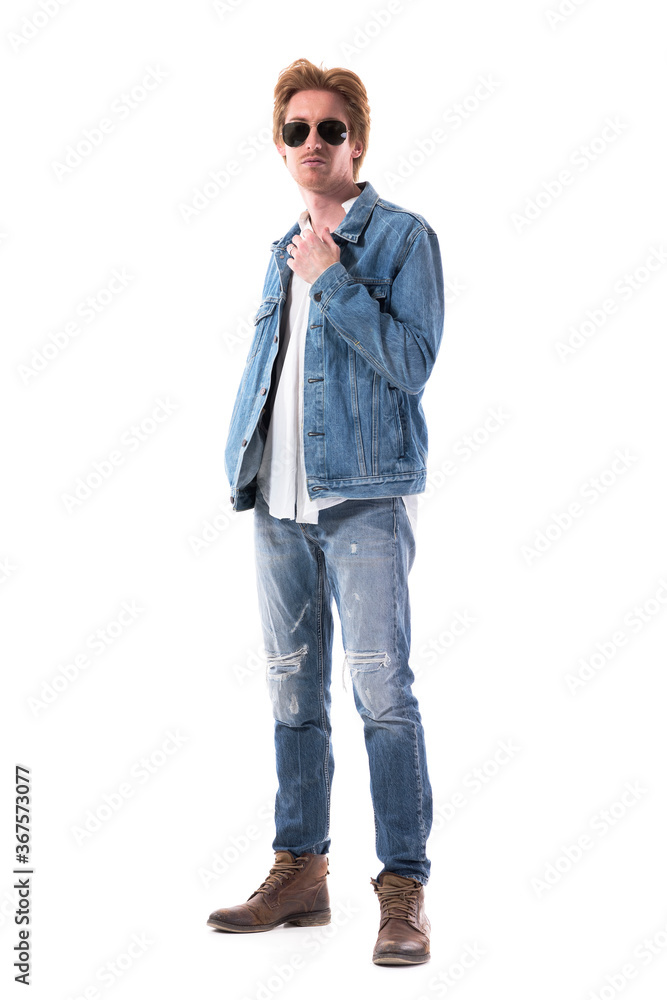 Side view of handsome elegant young man wearing jeans and denim jacket looking at camera. Full body length isolated on white background. Side view of handsome elegant young man wearing jeans and denim jacket looking at camera. Full body length isolated on white background.
